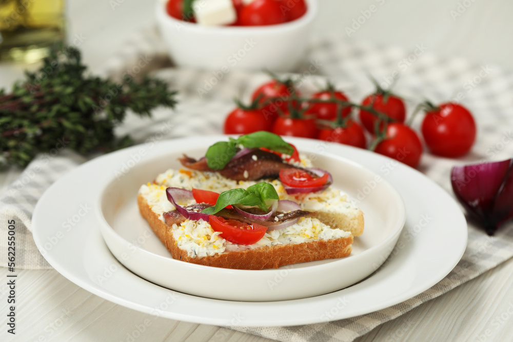 Delicious sandwiches with anchovies, tomato, onion and basil on white wooden table, closeup