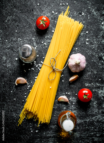 Raw spaghetti with garlic cloves and tomato.