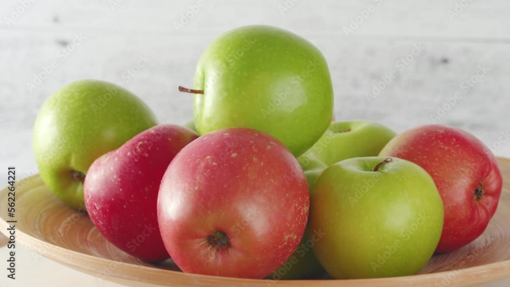 Red and green apples on a wooden plate close-up on a rustic background Red and green apples on a wooden plate close-up on a rustic background