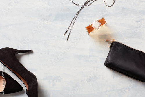 Still life of Black clutch purse, stiletto, perfume and necklace
