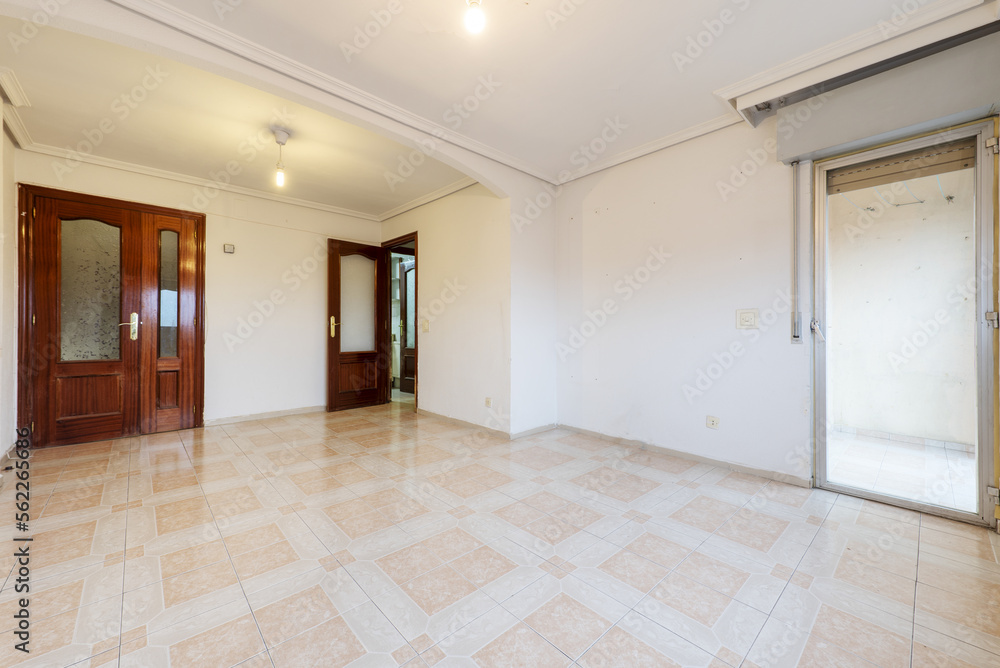 Empty living room with white walls and stoneware floor with a corner terrace and sapele wood double access doors Empty living room with white walls and stoneware floor with a corner terrace and sapele wood double access doors
