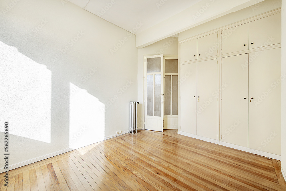 Empty house with a wall covered with white built-in cabinets with attics with trunks and doors of the same material with glass Empty house with a wall covered with white built-in cabinets with attics with trunks and doors of the same material with glass