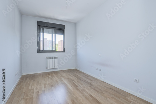 empty room with white walls and oak parquet flooring and ocher color anodized aluminum double window