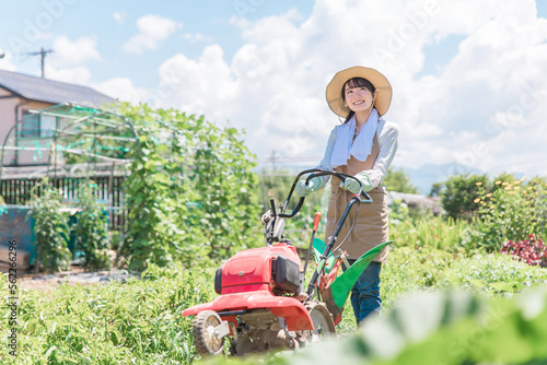 畑を小型トラクターで耕す農家のアジア人女性（農業・田舎暮らし）