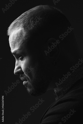 Making a hard decision concept. Profile portrait of charismatic 40-year-old man posing over black background. Short haircut. Classic, smart casual style. Close up. Black and white studio shot