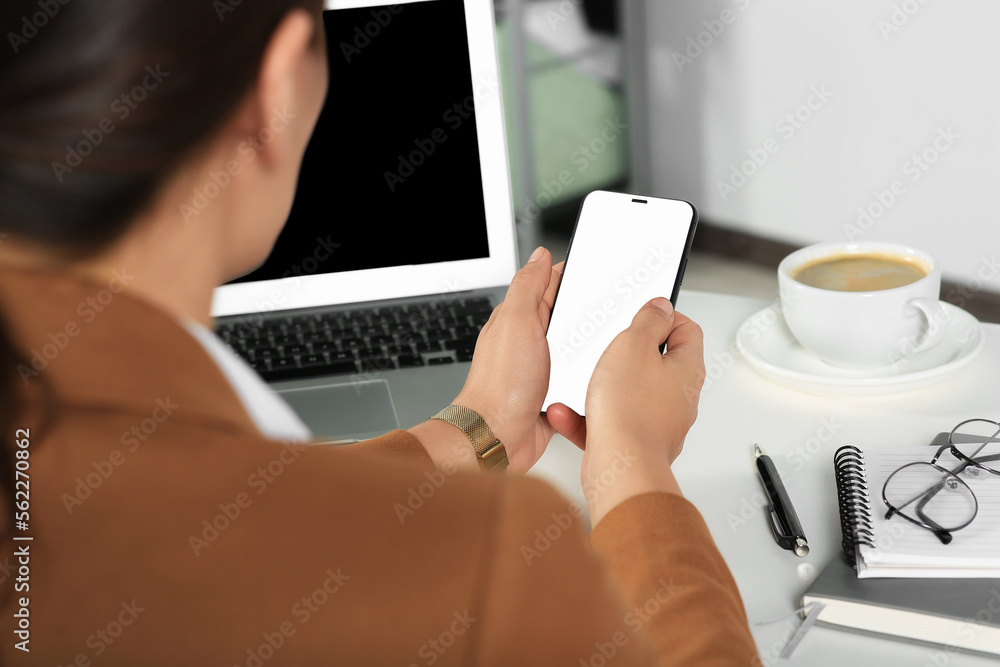 Woman using smartphone at table indoors, closeup Woman using smartphone at table indoors, closeup