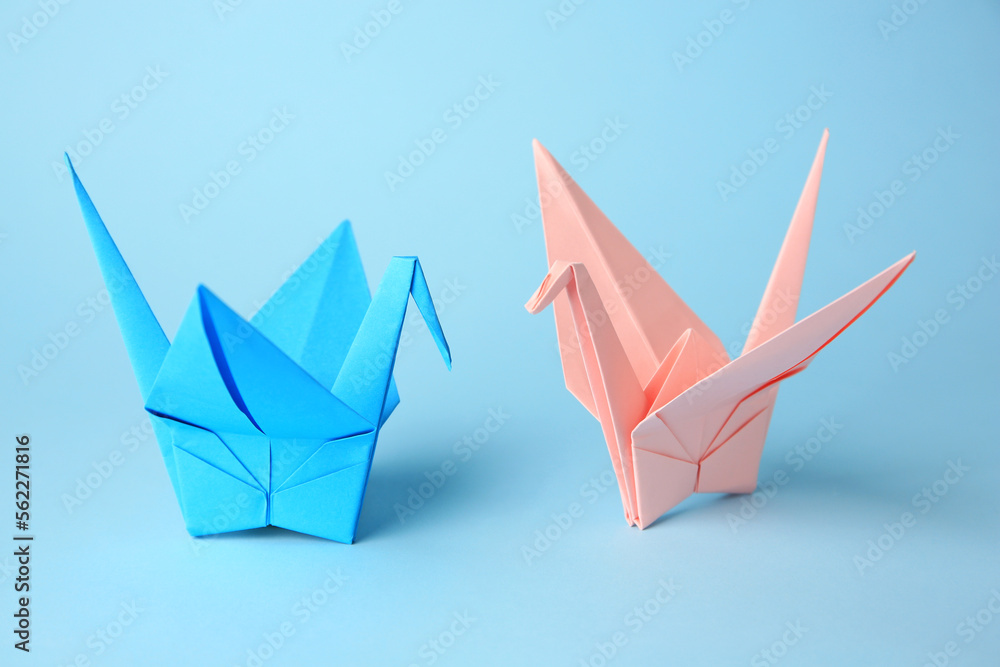 Fototapeta premium Origami art. Colorful handmade paper cranes on light blue background