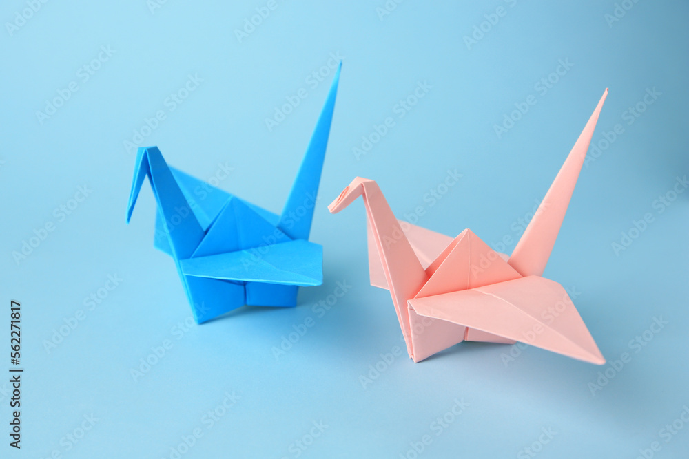 Fototapeta premium Origami art. Colorful handmade paper cranes on light blue background