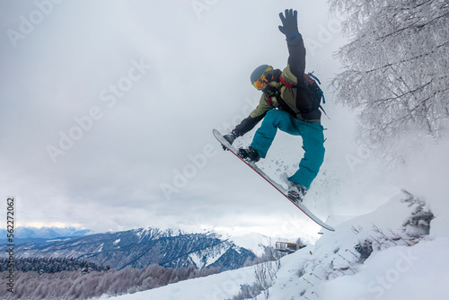 incredible snowboard jump under the white snowy forest on a good winter day, freeride in deep snow, ski season