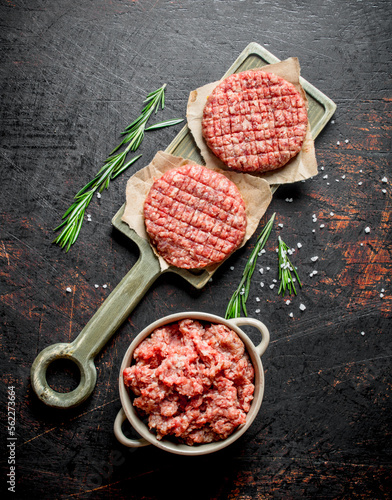 Raw burgers with ground beef and rosemary.