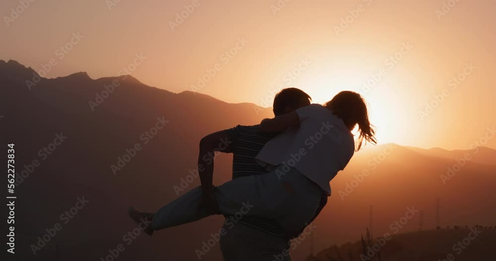 30s couple. Happy man spinning a woman on his back laughing enjoying honeymoon party together at sunset 30s couple. Happy man spinning a woman on his back laughing enjoying honeymoon party together at sunset