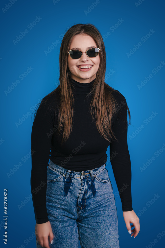 Hipster woman wearing sunglasses looking at camera posing over blue background. Hipster woman wearing sunglasses looking at camera posing over blue background.