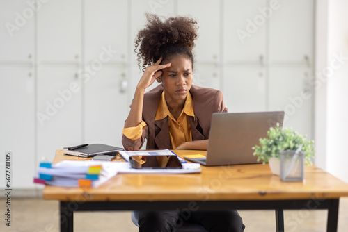 Portrait of tired young business african american woman work with documents tax laptop computer in office. Sad, unhappy, Worried, Depression, or employee life stress concept.