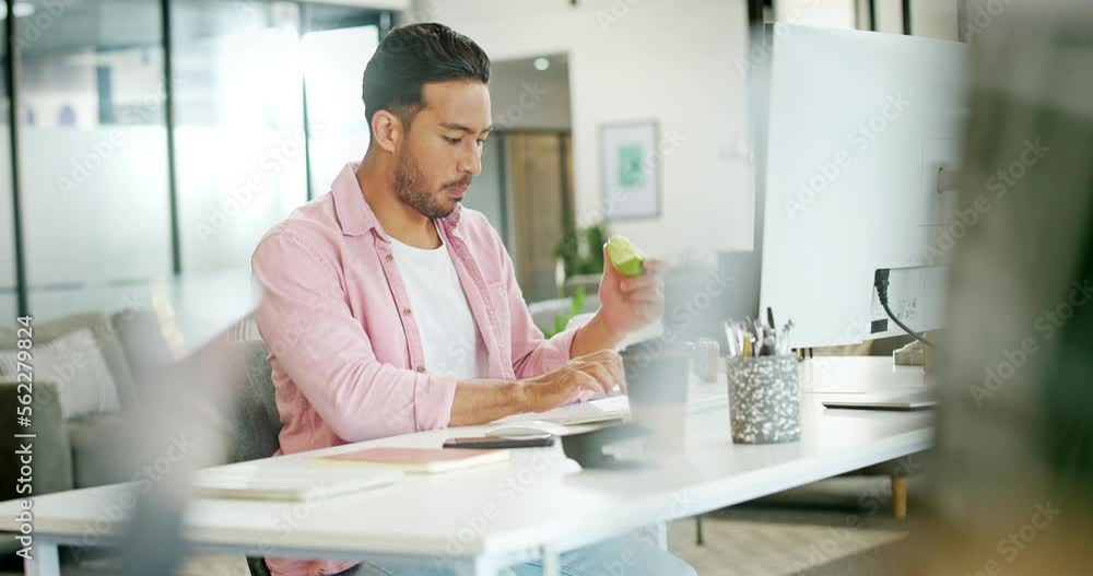 Asian man, working and eat apple in office for lunch time snack, planning tech strategy on pc and checking phone. Businessman, smartphone and typing on computer with healthy food for diet nutrition