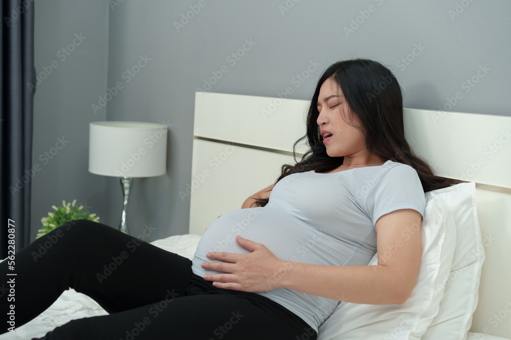 pregnant woman has a stomachache on bed pregnant woman has a stomachache on bed