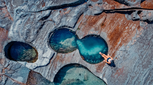 Closeup Drone Aerial of Girl Sitting At Edge of Famous Figure 8 Pool In Royal National Park, Australia