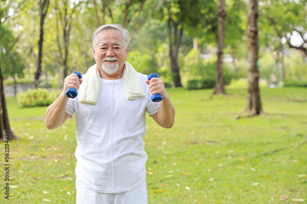 Happy and smiling asian senior man doing arm work out and lifting dumbbell exercise with relaxation for healthy in park outdoor after retirement. Health care elderly outdoor lifestyle concept. Happy and smiling asian senior man doing arm work out and lifting dumbbell exercise with relaxation for healthy in park outdoor after retirement. Health care elderly outdoor lifestyle concept.