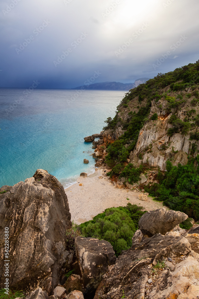 Sandy Beach on a rocky coast near Cala Gonone, Sardinia. Cloudy Sunrise Sky.
