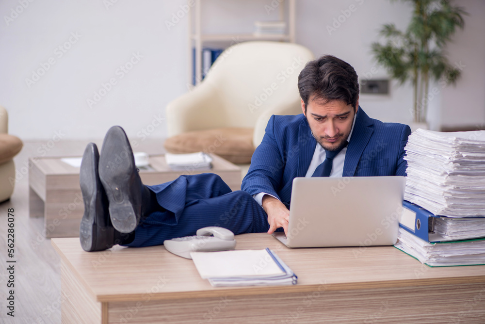 Young male employee and too much work in the office Young male employee and too much work in the office