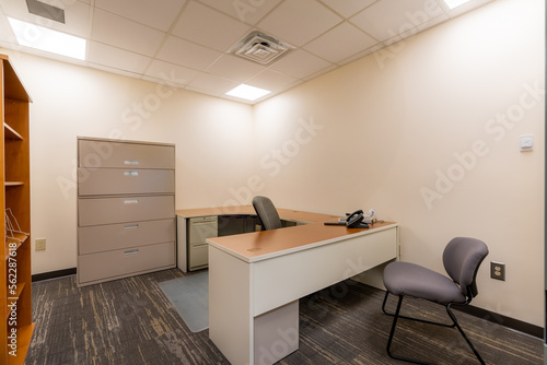 Depressing dull office with no window.  Typical uninspiring empty office with desk, chair, file cabinet.