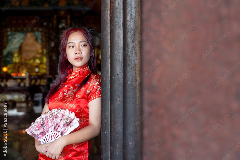 Fototapeta premium portrait of beautiful asian woman in traditional Chinese dress holding fan in Chinese shrine in Chinese new year festival celebration