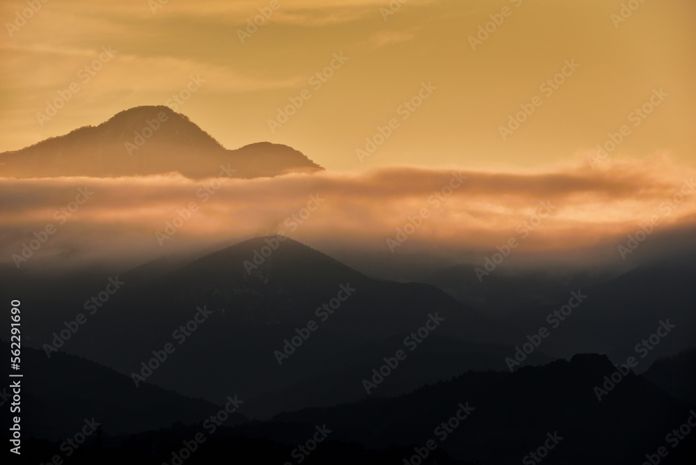 美しい夕日が差す山間と流れる雲海