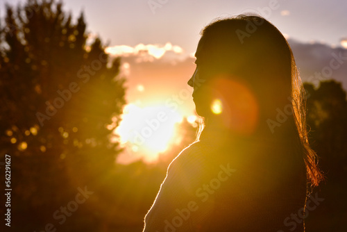 朝日を背景にしたシルエットのアジア女性