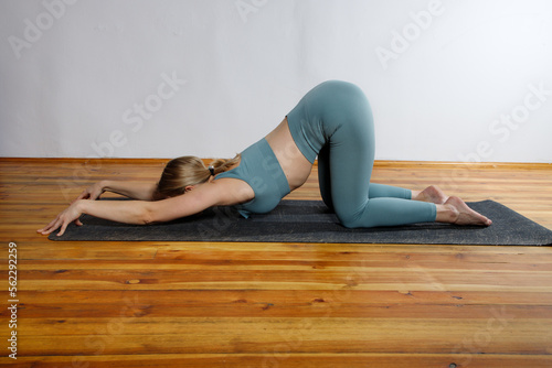 Caucasian blonde yoga woman in green clothes practicing sport pose indoor