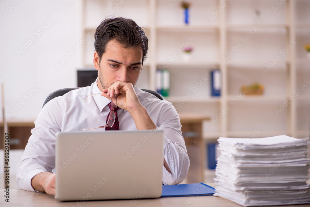 Young male employee and too much work in the office