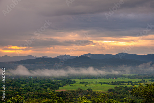 A bird's-eye view of field countryside Surrounded by mountains and nature in the rainy or farming season at Wat Phra That Doi Phra Chan of Lampang Province, Thailand. © stpadcharin