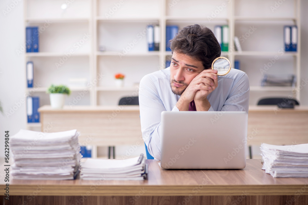 Young male employee and too much work in the office Young male employee and too much work in the office