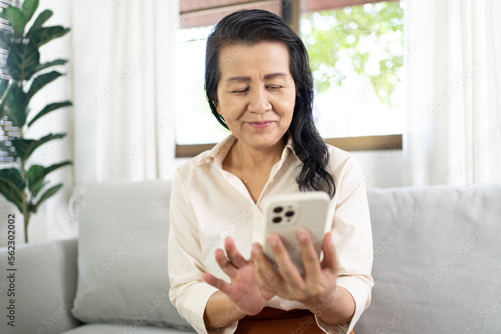 Middle age Asian woman holding cell telephone Work from home. smiling Beautiful mature asian woman VDO Call Conference smart phone with technology concept