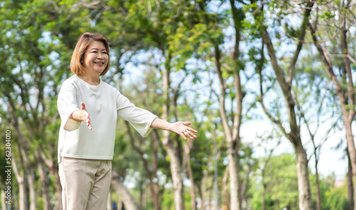 Portrait of happy senior old adult elderly asia women smiling standing and stretch her arms relax and enjoy with nature feeling breath fresh clean air in green park.Healthcare