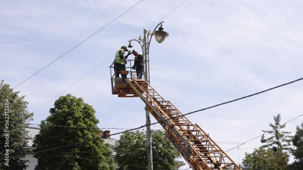 repair street lamp, crane lifted, light bulb. Worker is fixing street