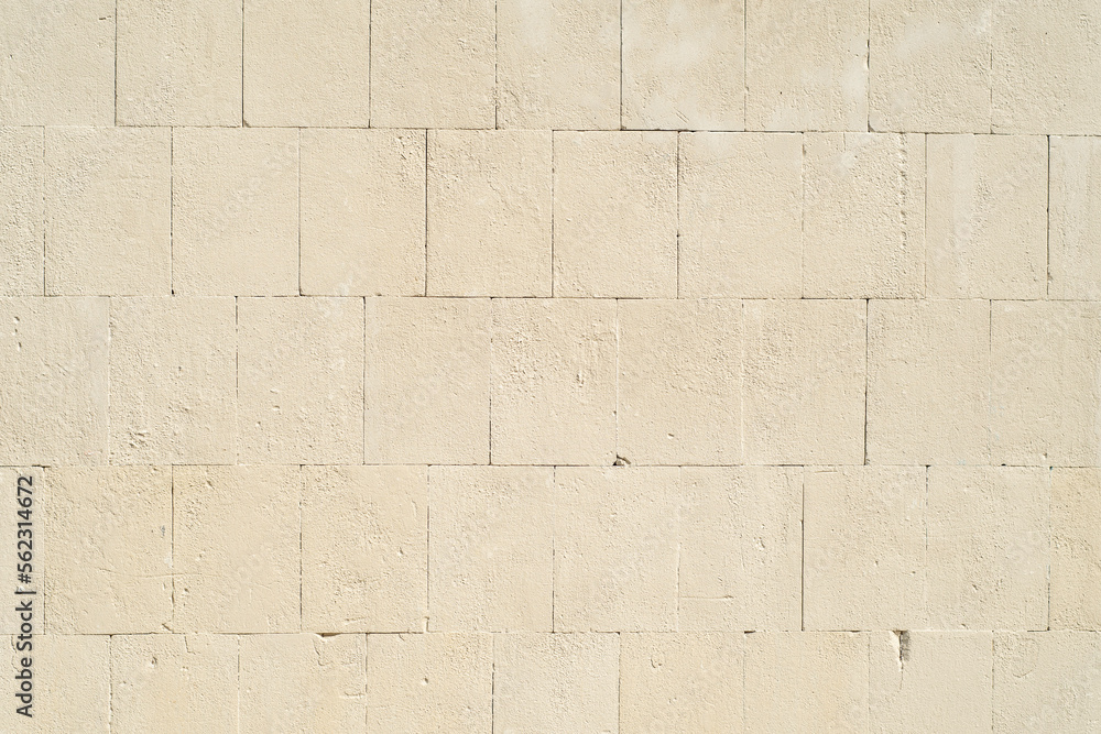 Background with a stone wall made of large blocks painted with beige paint Background with a stone wall made of large blocks painted with beige paint