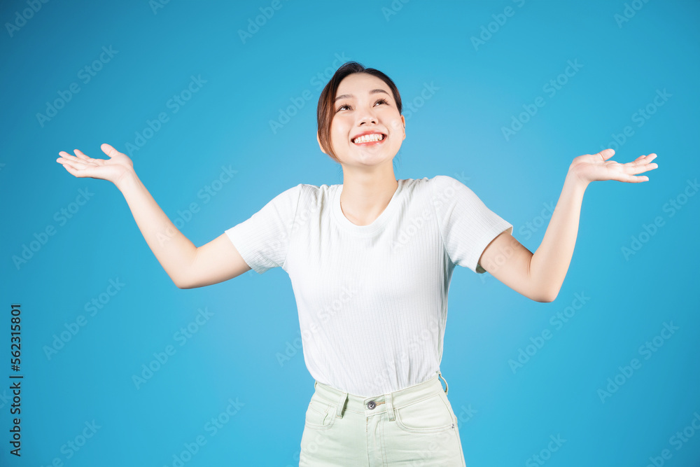 Portrait of young Asian woman standing on blue background Portrait of young Asian woman standing on blue background