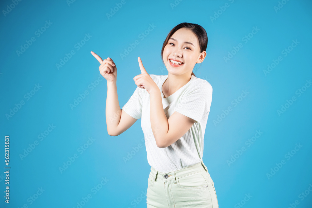Portrait of young Asian woman standing on blue background Portrait of young Asian woman standing on blue background