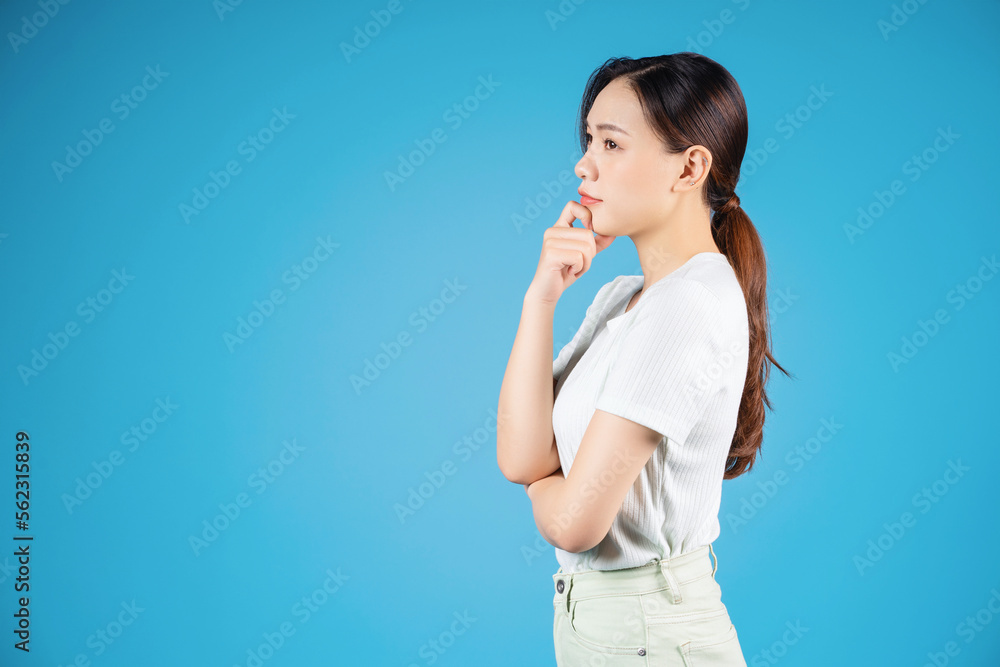 Portrait of young Asian woman standing on blue background Portrait of young Asian woman standing on blue background