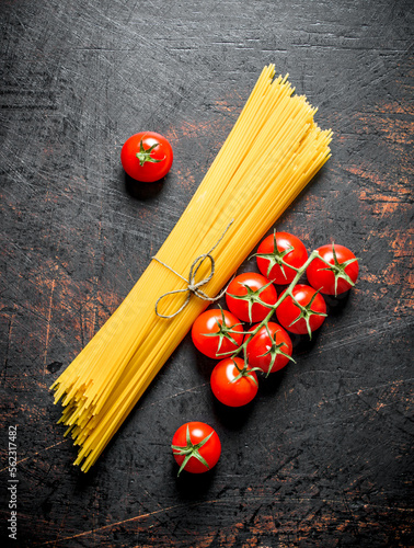 Raw spaghetti with tomatoes on a branch.