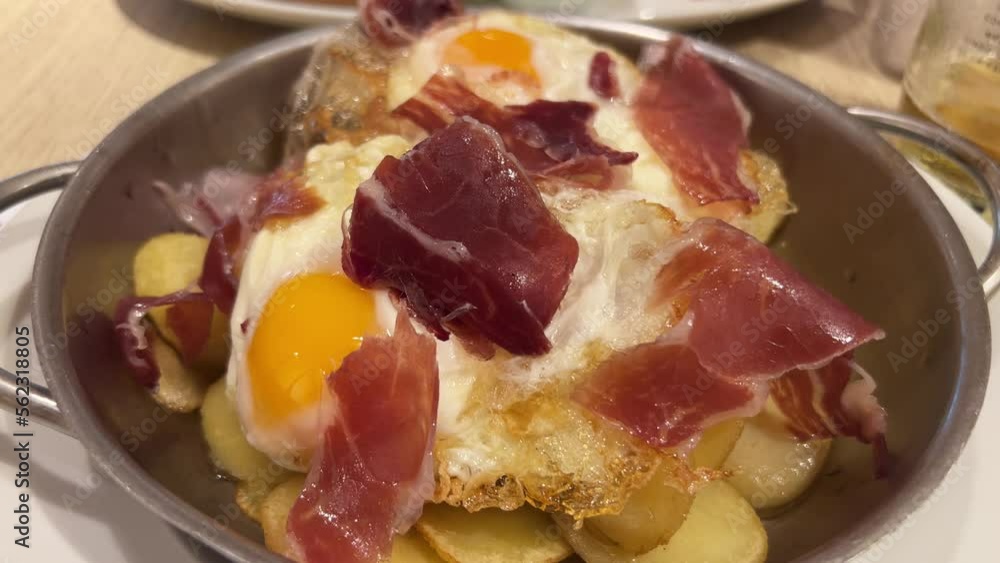 National Spanish tapa with Iberian ham, eggs, and potatoes in a pan at a restaurant in Spain, traditional breakfast dish, 4K shot National Spanish tapa with Iberian ham, eggs, and potatoes in a pan at a restaurant in Spain, traditional breakfast dish, 4K shot