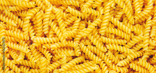 Raw dry fusilli pasta, food background texture, top view horizontal banner