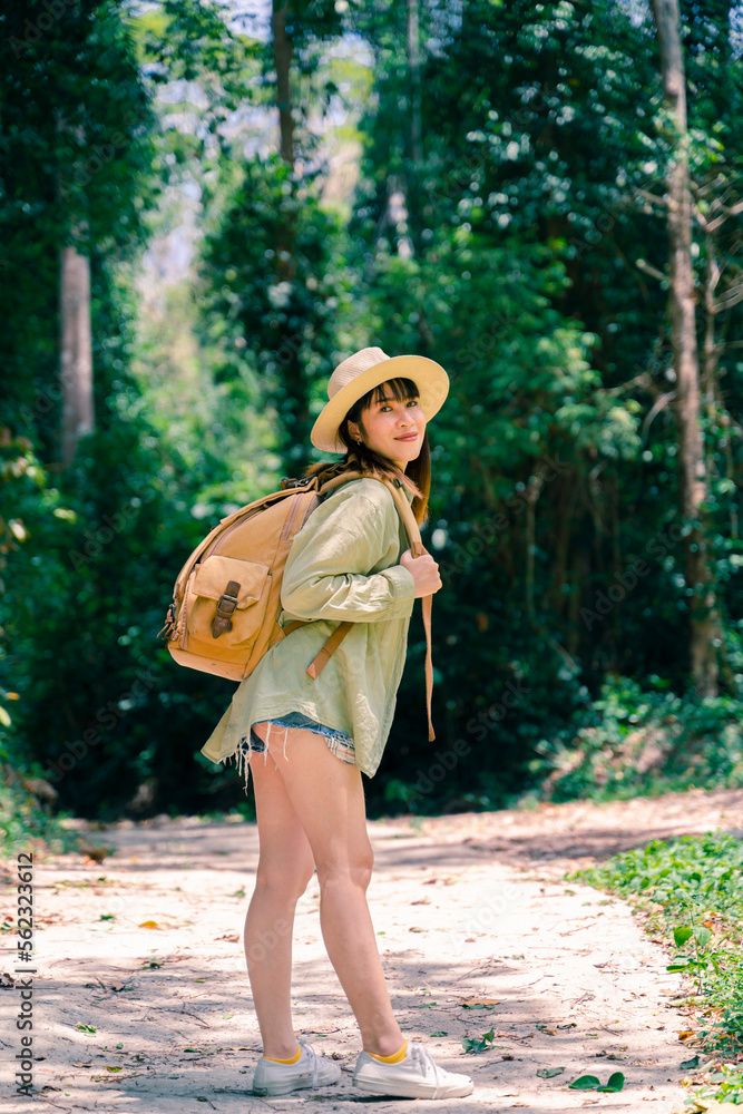 Young beautiful woman in autumn fashion with leather backpack traveling in nature of Thailand with autumn leaves.
