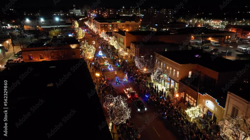 Wide aerial drone shot flying over brightly lit holiday Christmas parade at night Wide aerial drone shot flying over brightly lit holiday Christmas parade at night