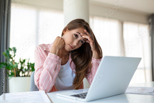Exhausted businesswoman having a headache in modern office. Creative woman working at office desk feeling tired. Stressed casual business woman feeling head pain while overworking on desktop computer.