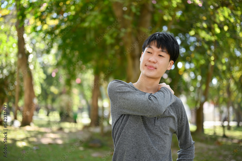 Happy young Asian man in casual clothes relaxing in the beautiful greenery park on the weekend. Happy young Asian man in casual clothes relaxing in the beautiful greenery park on the weekend.