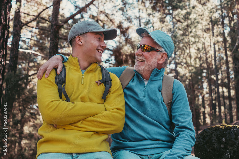 Happy couple of senior grandfather and young grandson hiking together in the woods sharing the passion for nature and healthy lifestyle.