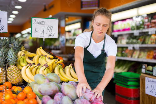 Fotografie Focused fifteen-year-old girl who works part-time in a store as a trainee salesw