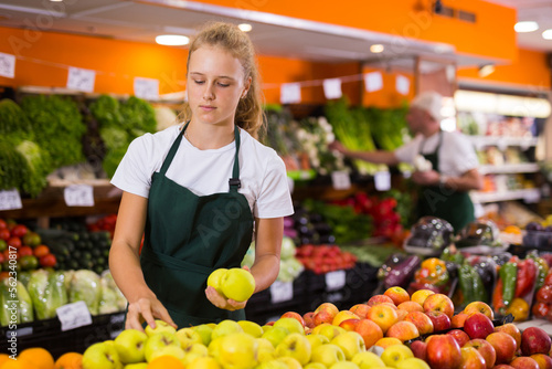 Obraz na plátně Fifteen-year-old girl who works part-time in a store as a trainee saleswoman put