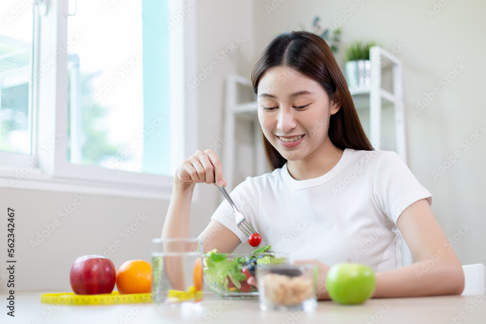 asian females using smartphones and taking notes eating healthy food each day with vegetables fruit on table. health and care concept. asian females using smartphones and taking notes eating healthy food each day with vegetables fruit on table. health and care concept.