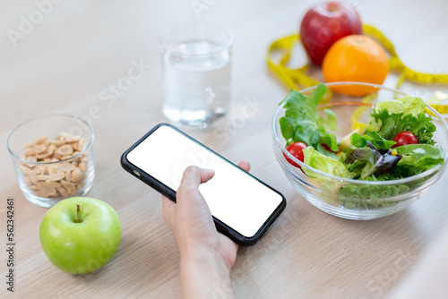 smartphone white screen display blank in hand woman with healthy food diet vegetable salad fresh on table. application and healthy food concept.